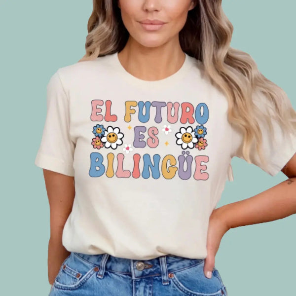 Person wearing a t-shirt with 'El Futuro Es Bilingue' text and colorful design on a light blue background