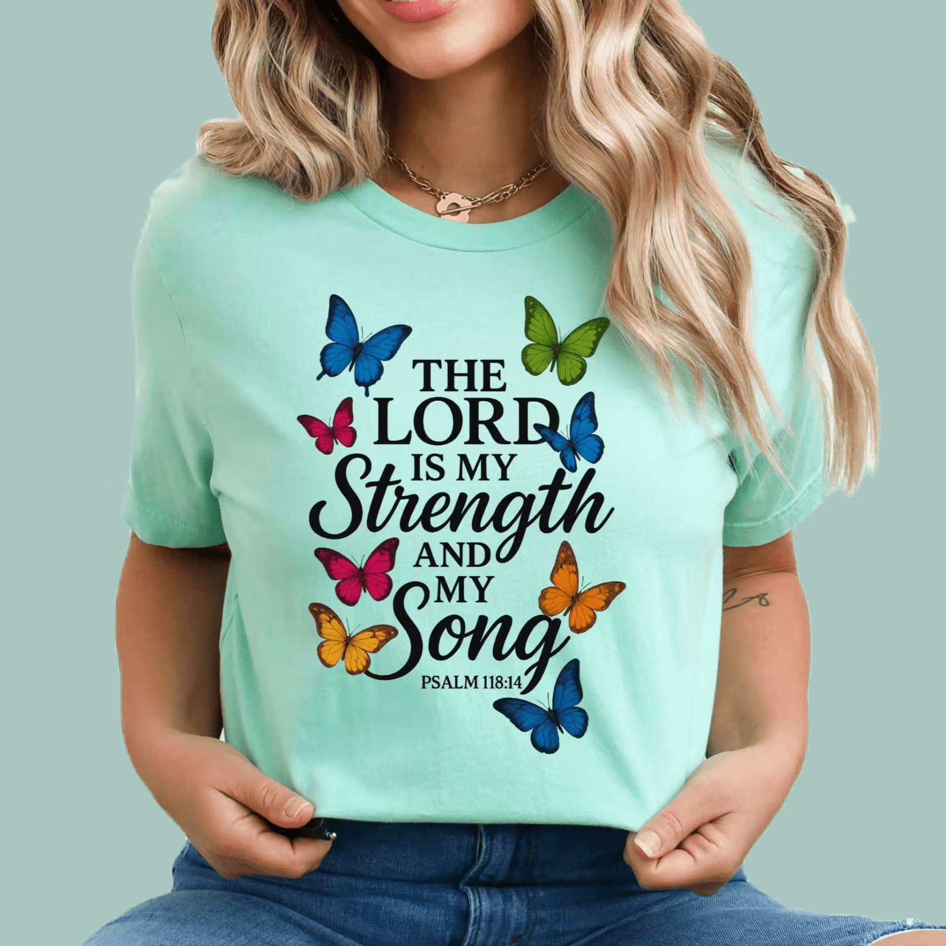 Person wearing a light blue t-shirt with butterfly design and text on a solid background