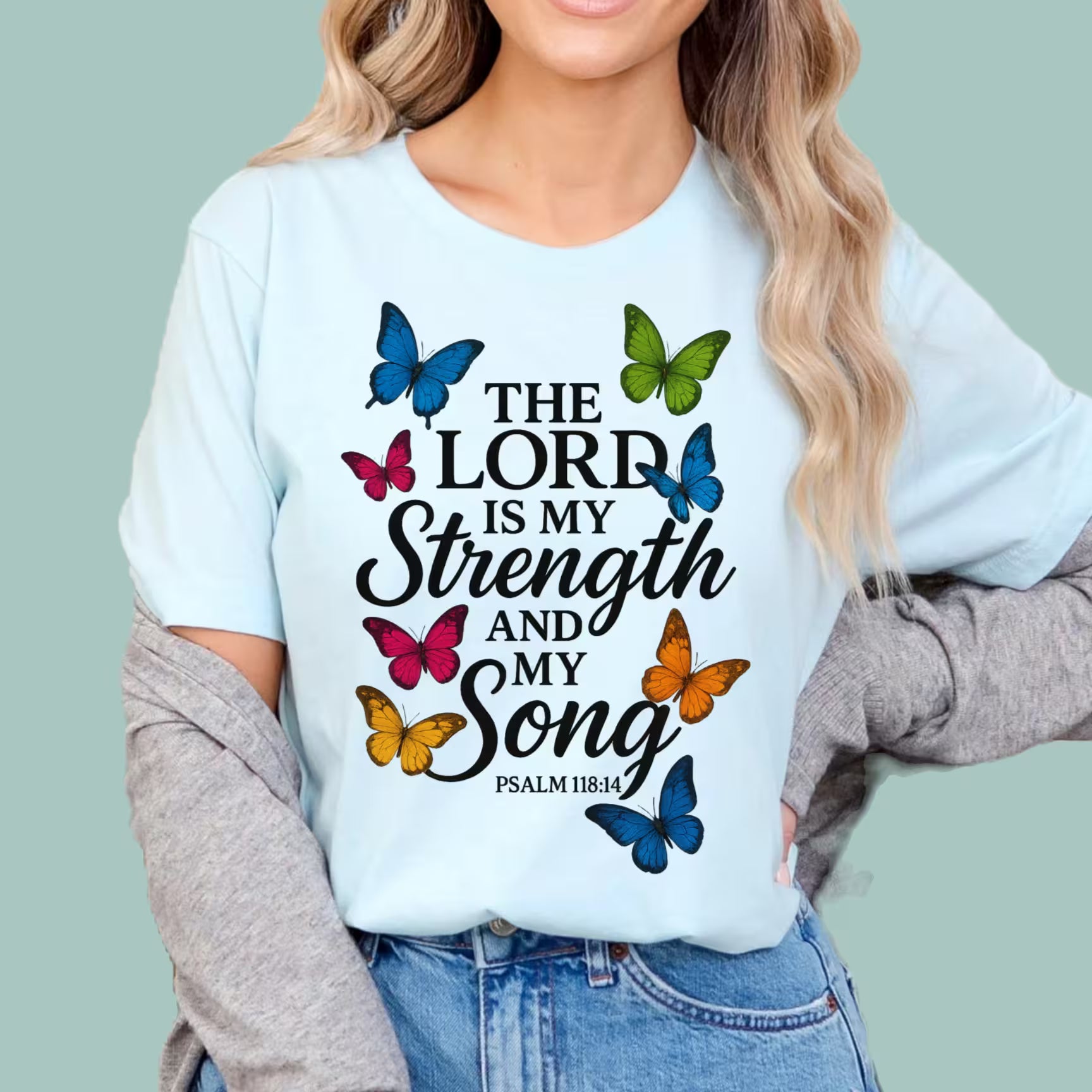 Person wearing a light blue t-shirt with butterfly design and text on a plain background