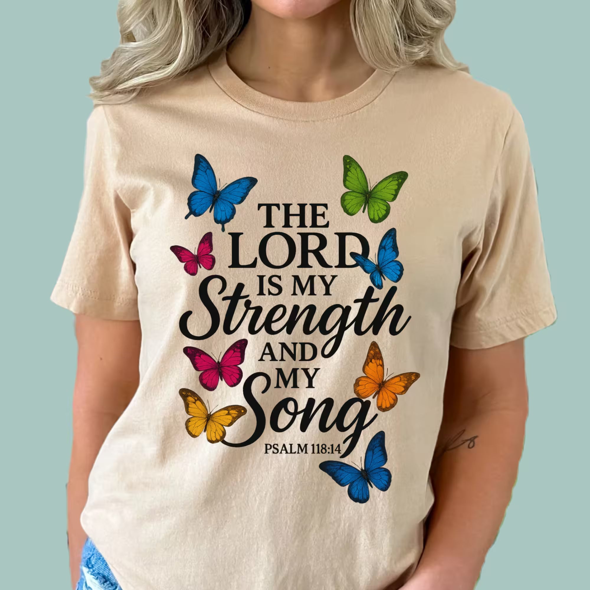 Beige t-shirt with colorful butterfly graphics and text on a light blue background