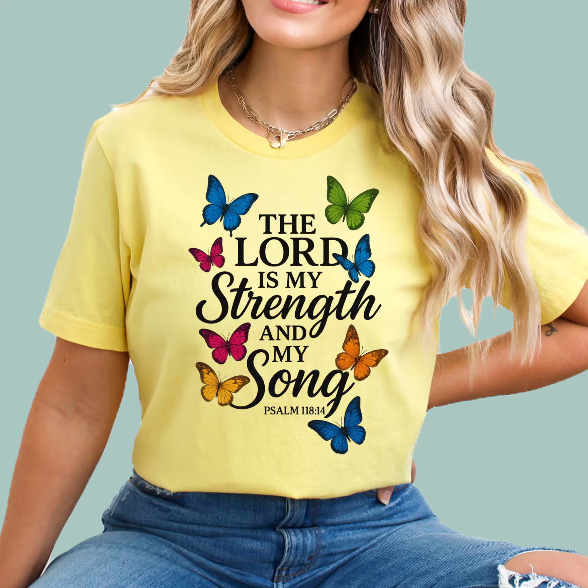 Person wearing a yellow t-shirt with butterfly design and text on a light blue background