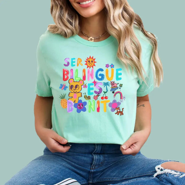 Person wearing a light green t-shirt with colorful text and graphics on a plain background