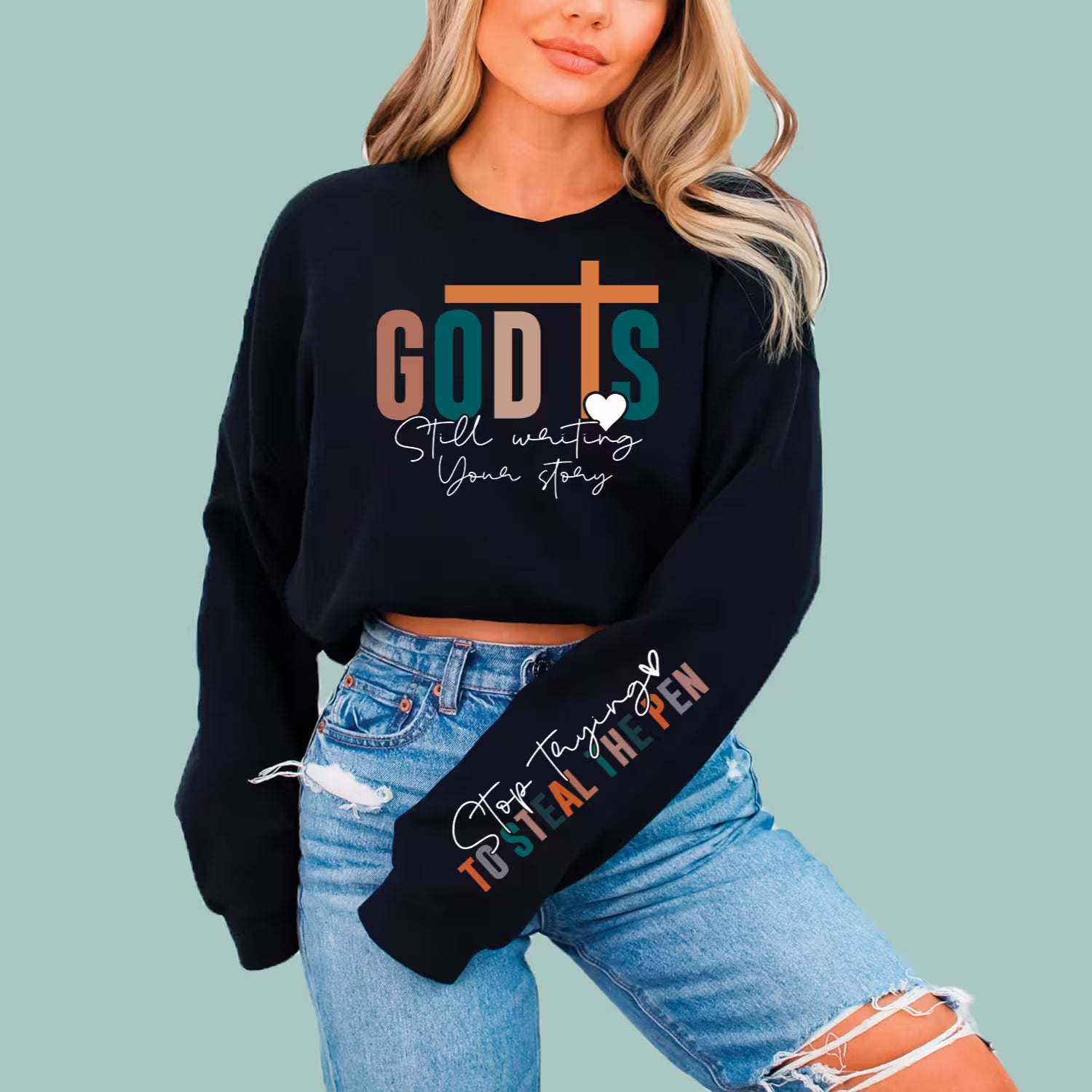 Black "God Is Still Writing Your Story" sweatshirt, modern Christian apparel for daily encouragement.