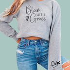 Grey floral-inspired faith sweatshirt featuring "Bloom With Grace" typography for a minimalist Christian look.