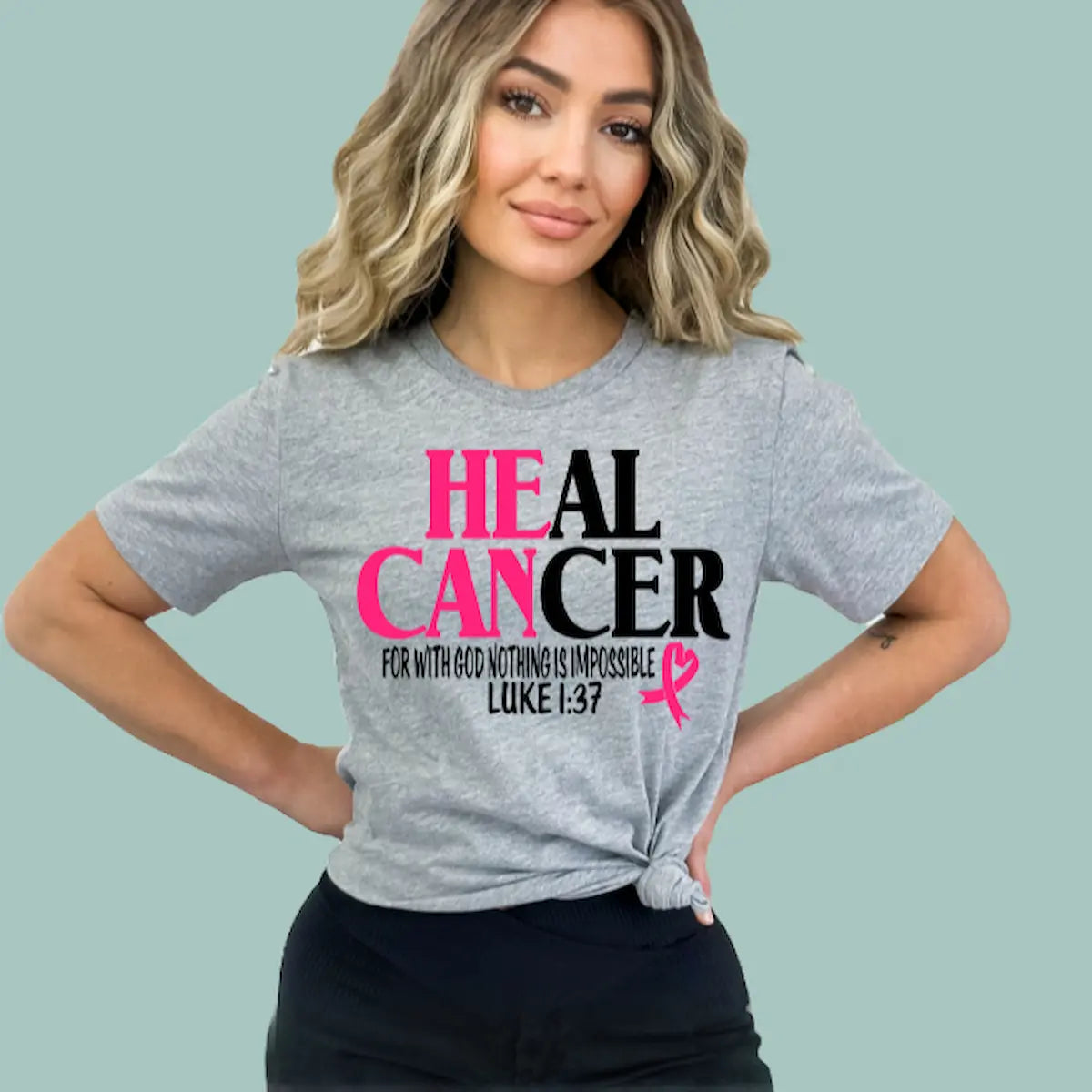 Woman wearing a grey 'Heal Cancer' t-shirt with the scripture Luke 1:37 and a pink ribbon.