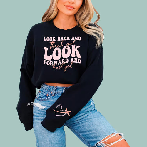 Woman wearing a black "Look Back & Trust God" Christian sweatshirt with a white and pink script graphic.