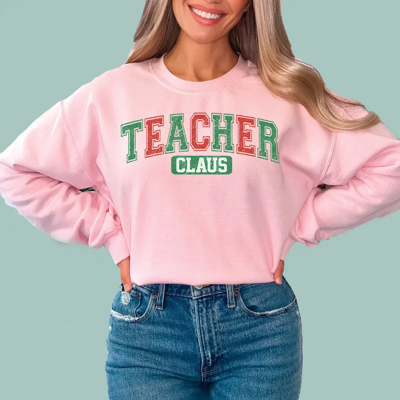 Pink festive teacher sweatshirt with "Teacher Claus" graphic, ideal for school holiday parties.