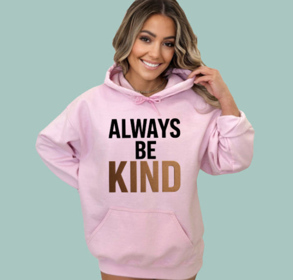 Woman wearing a pink hoodie with 'Always Be Kind' text on a light blue background