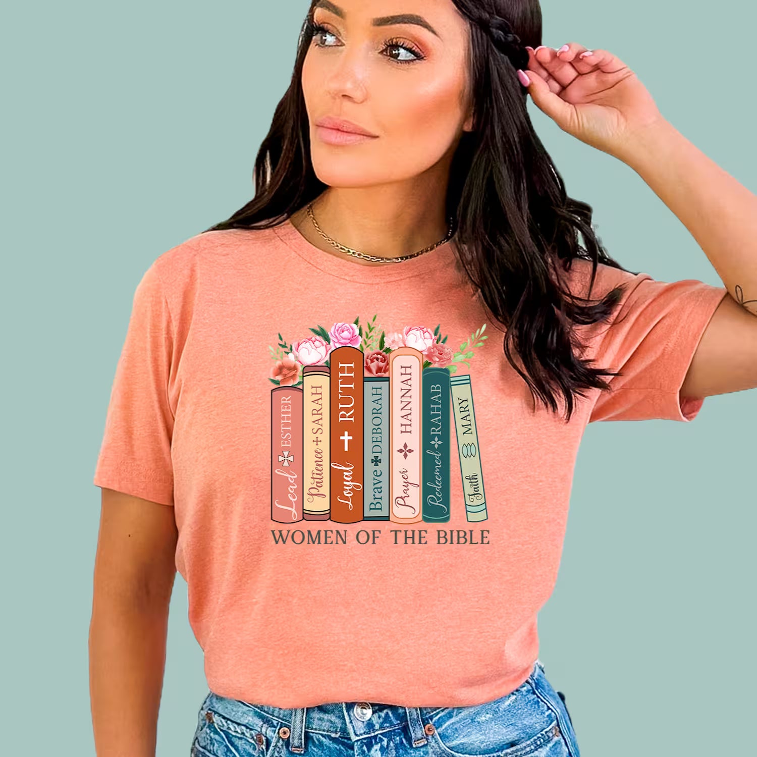 Woman wearing a Sunset Christian t-shirt featuring a stack of books with names like Esther, Ruth, and Mary.